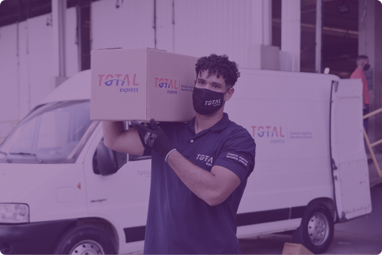 Foto de homem com o uniforme da Total Express e máscara respiratória segurando uma caixa de papelão com o logotipo da empresa